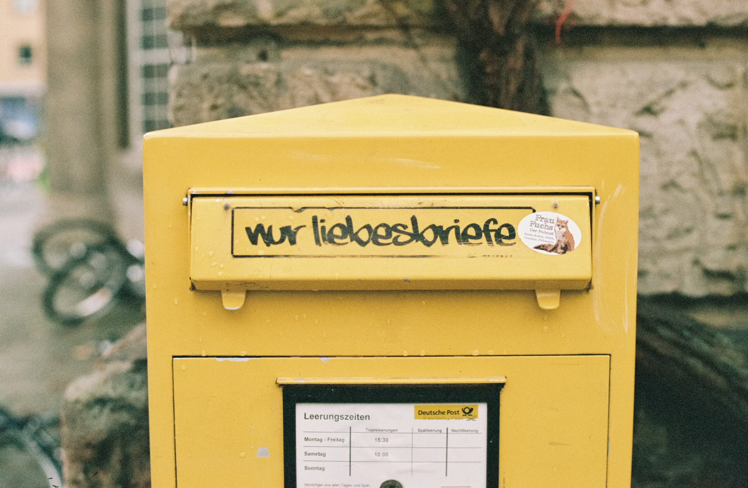 Gelber Briefkasten mit Graffiti: "nur liebesbriefe"
